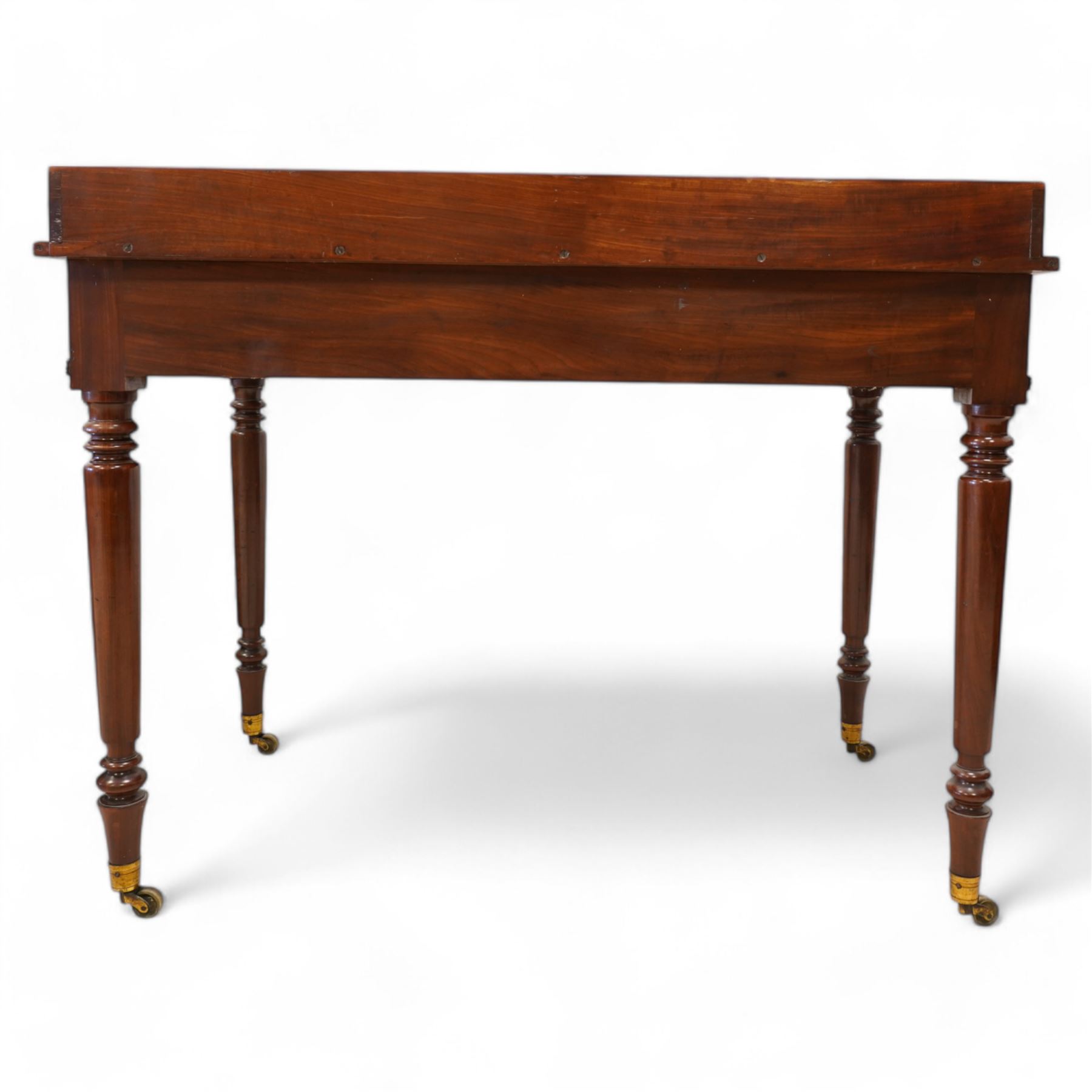 Gillows, Lancaster - early 19th century mahogany writing table, reeded three-quarter gallery over rectangular top with reed moulded edge, fitted with three cocked-beaded drawers with turned handles, the central drawer stamped 'Gillows Lancaster'. on turned supports with brass cups and castors 