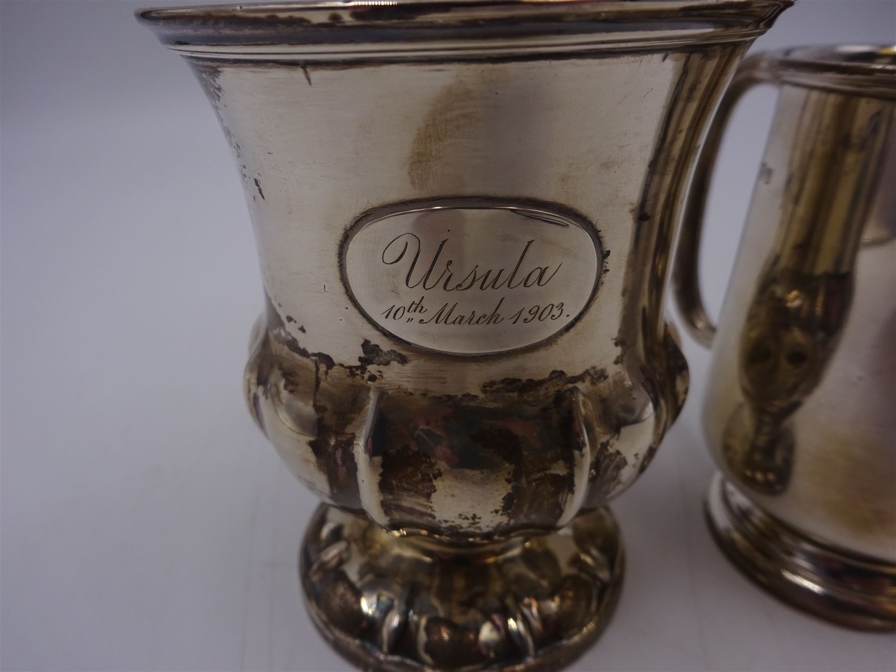 Two silver christening mugs, the first a Victorian example, of part fluted waisted form, upon circular foot with scroll handle, hallmarked Edward, John & William Barnard, London 1838, the second example of plain slightly tapering form with C handle, hallmarked S Blanckensee & Son Ltd, Chester 1929, tallest H9cm