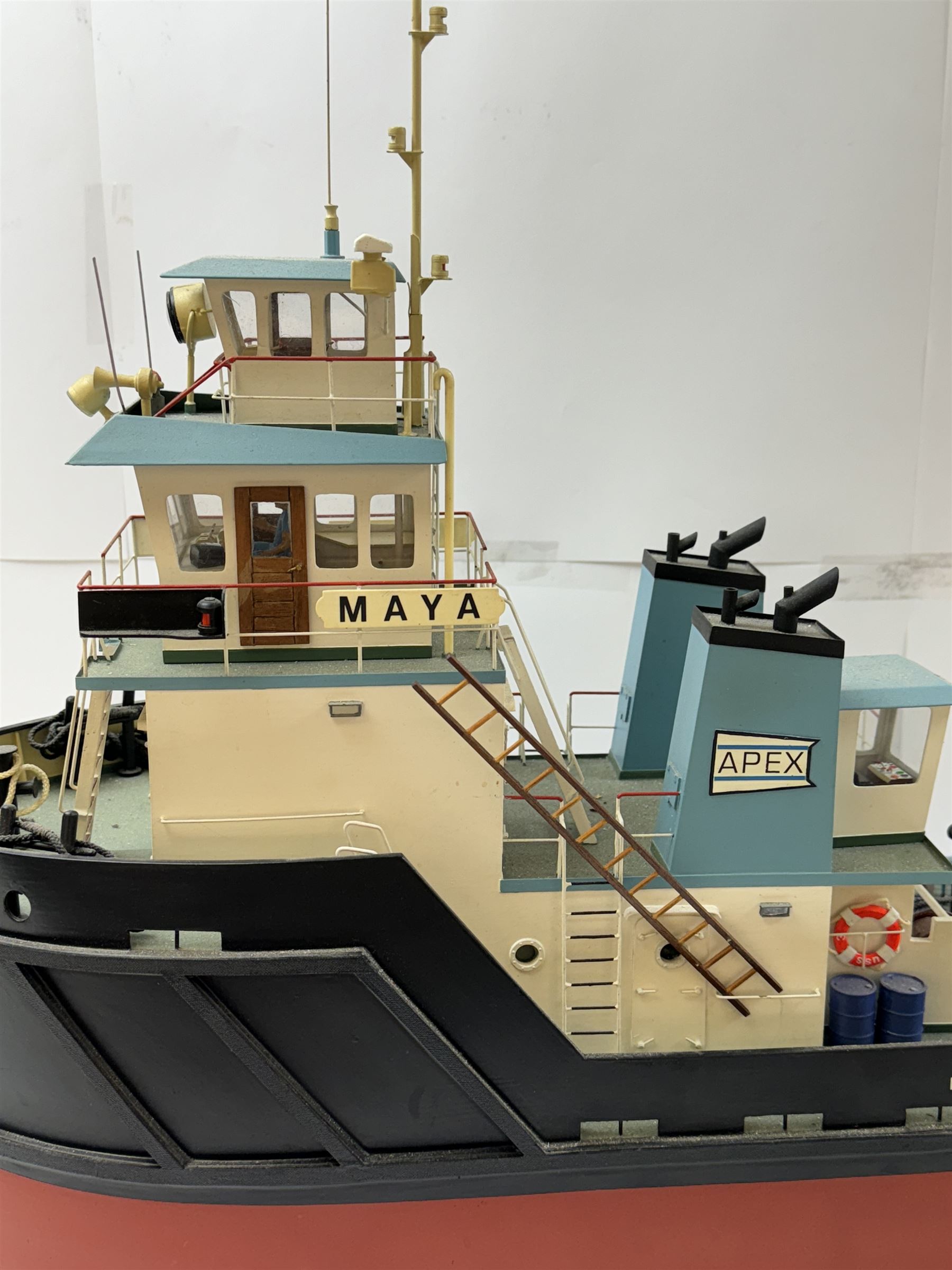 Modern model of American Coastal and River Tugboat 'Maya', in red, black and light blue finish, upon a green stand inscribed with name, H53cm, W52cm 