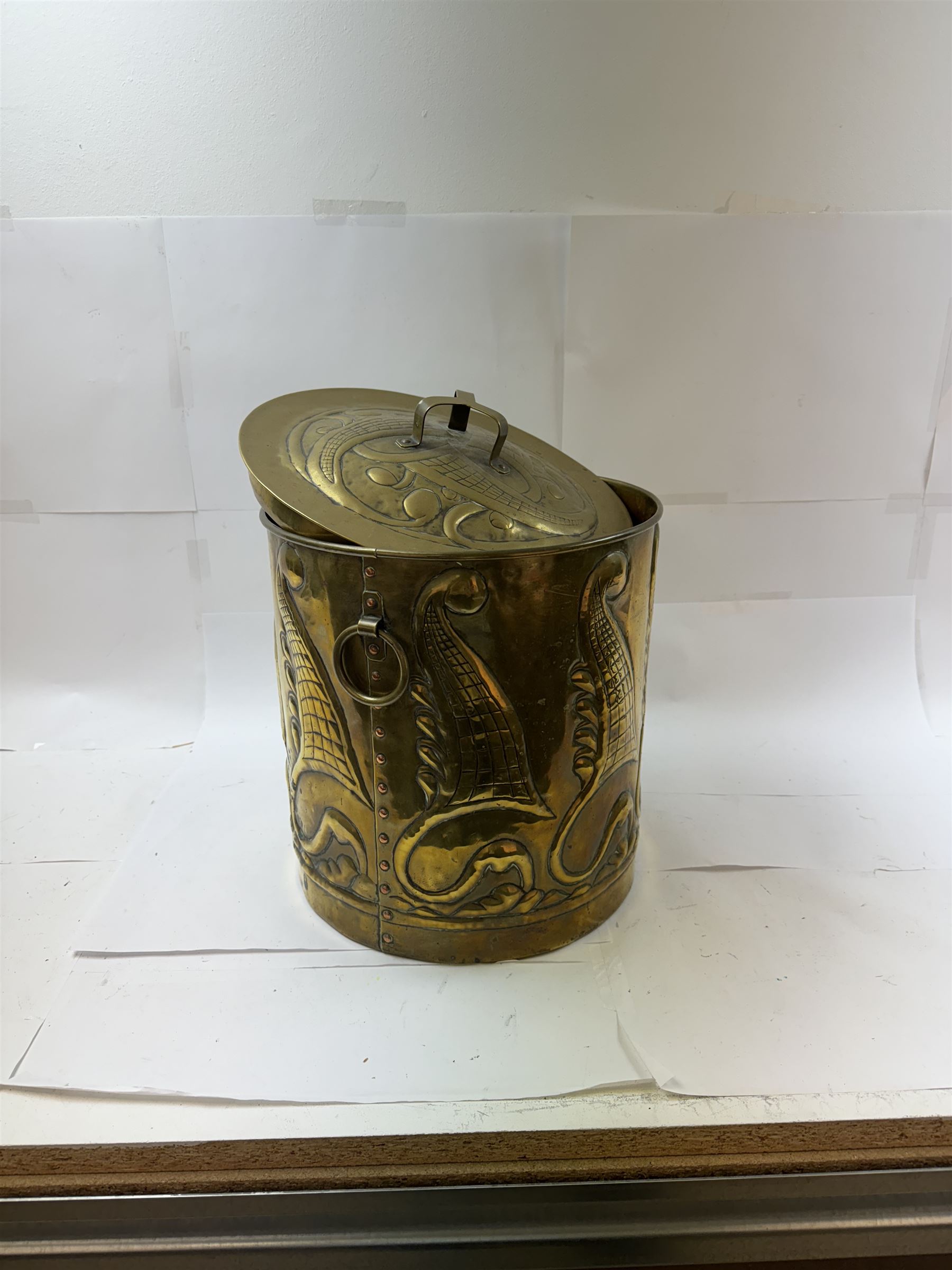 Arts and Craft brass coal box of cylindrical, with embossed stylised leaf panels, with twin handles, the cover with triform handle, H42cm 