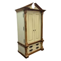 Hardwood and cream painted kitchen larder cupboard, sloped pediment over two panelled doors, the interior fitted with slides, drawers and storage shelves, two long drawers below, mounted by turned pilasters, on metal bound moulded plinth base