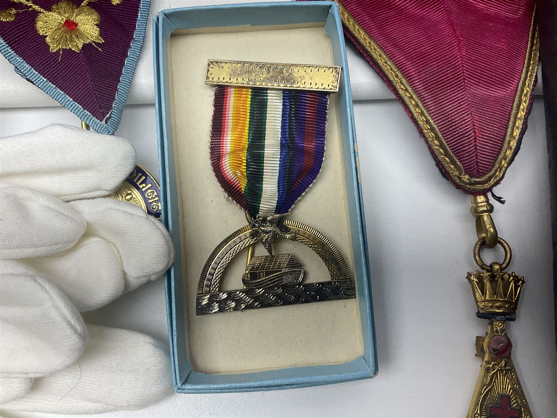 Masonic regalia, including two silver-gilt medals/jewels, centenary medal, aprons, and sash etc, housed in brown briefcase