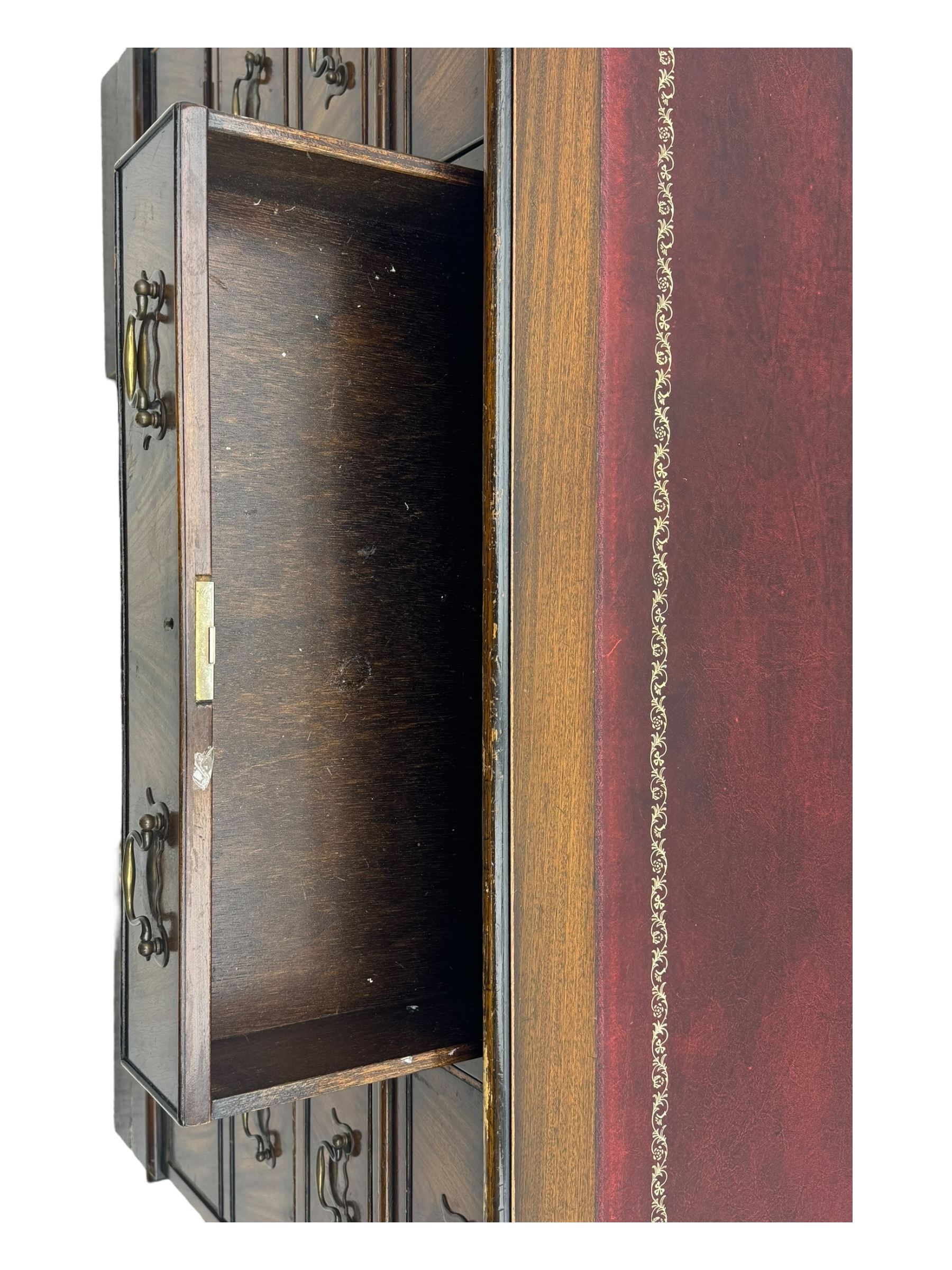 20th century mahogany twin pedestal desk, moulded rectangular top with red leather inset with gilt tooled border, central drawer over kneehole flanked by two banks of four graduating cockbeaded drawers, on plinth base