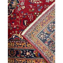 Persian Meshed red ground rug, central floral rosette medallion surrounded by trailing branch and stylised flower heads, repeating scrolling border