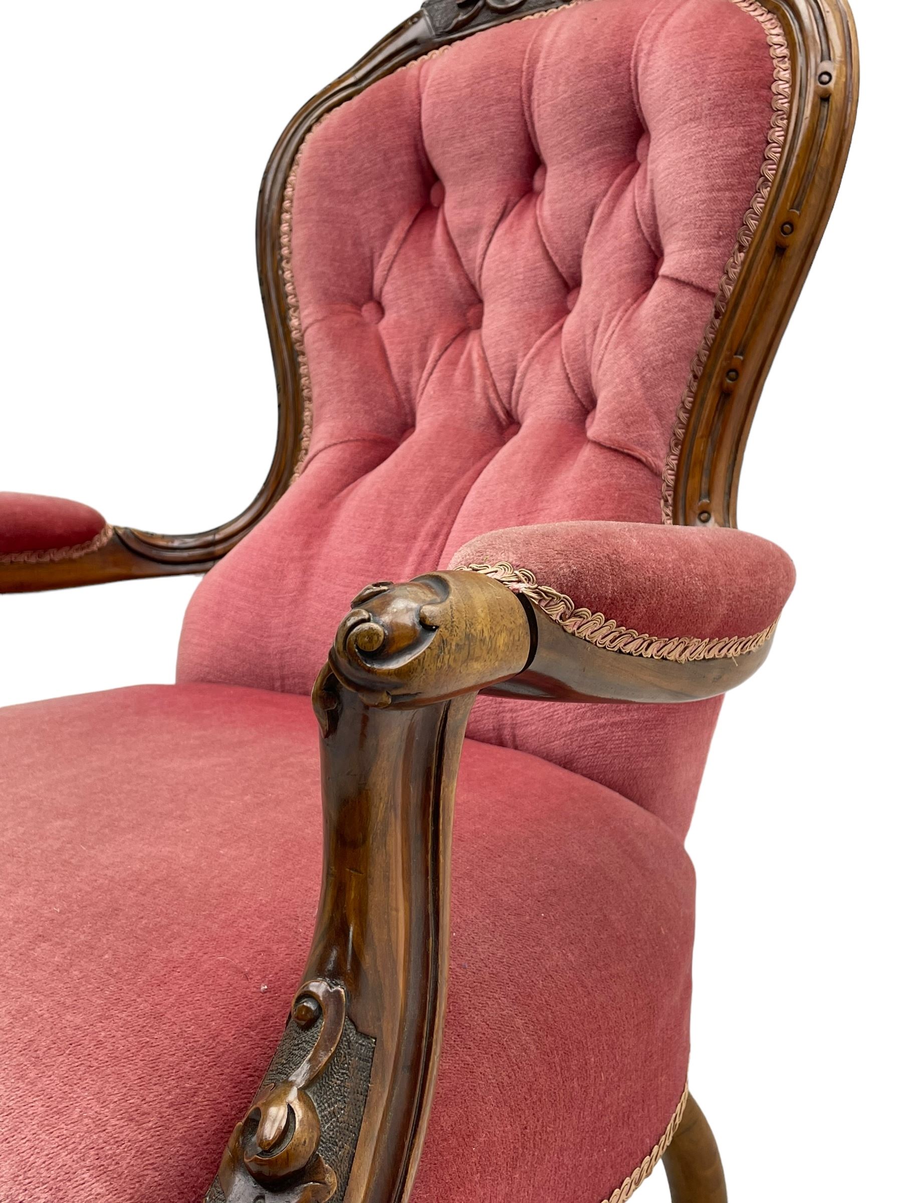 Victorian carved walnut open armchair, foliate carved cresting rail over butted back and sprung seat, upholstered in pink velvet scrolled arm terminals with moulded scrolling vines terminating to cabriole supports and ceramic castors