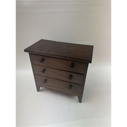 19th century mahogany miniature chest of drawers, with three graduating drawers, each with wooden handles, with inlaid shaped front and upon four bracket feet, H24cm