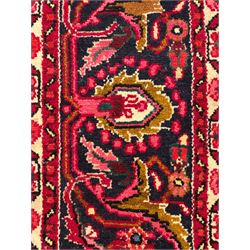 Persian Nanaj crimson ground carpet, the busy field filled with interconnecting stylised plant motifs with scrolling branches, the guarded indigo border decorated with repeating palmettes and foliate patterns