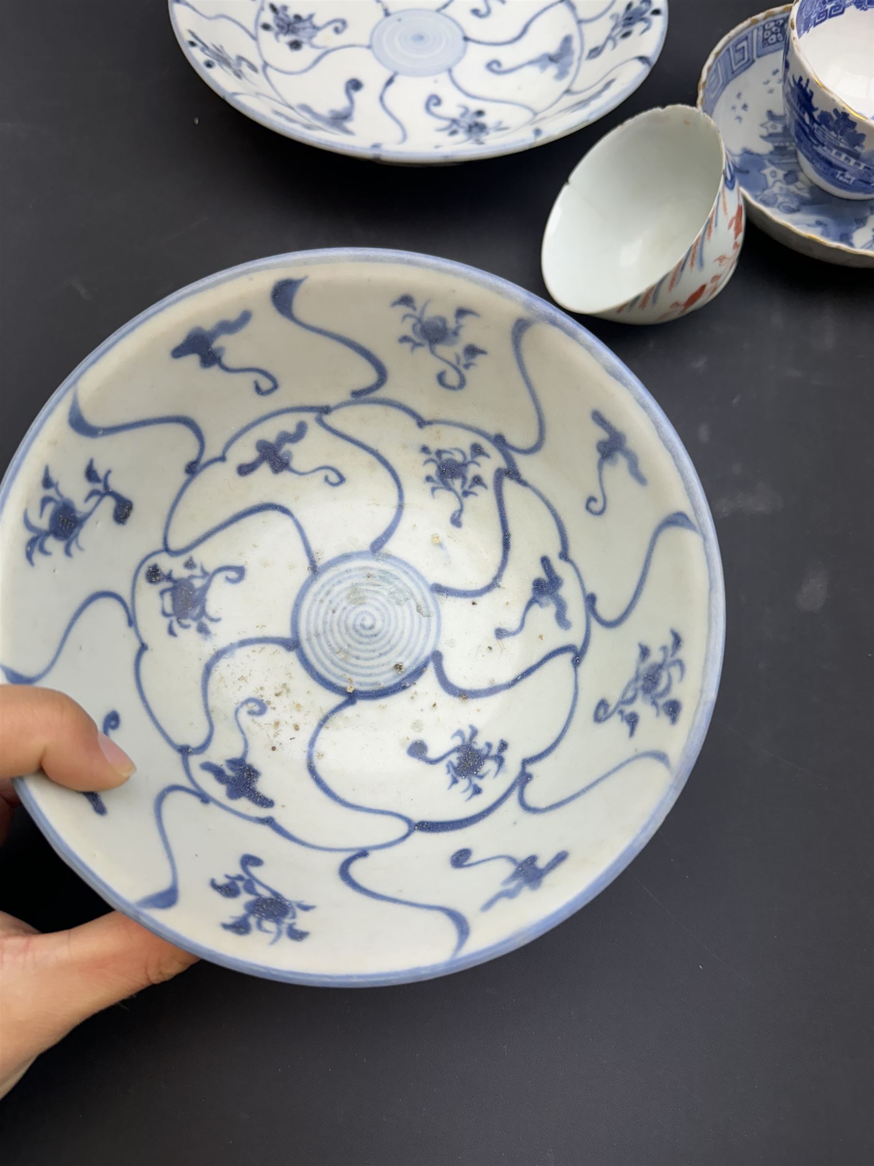 Early 19th century Chinese Tek Sing bowl, decorated with stylised blossoms, with 'Nagel Auctions' label to base, H6.5cm D15.5cm, together with a  Tek Sing similar saucer, D18cm, a Chinese tea bowl decorated in blue and red blossoming flowers, a Chinese blue and white saucer, and an English blue and white Willow pattern tea bowl, (5)