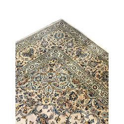 Central Persian Kashan pale khaki ground carpet, shaped central medallion enclosing small stylised motifs, the field decorated profusely with trailing foliate branches and plant motifs, guarded border with repeating floral design 