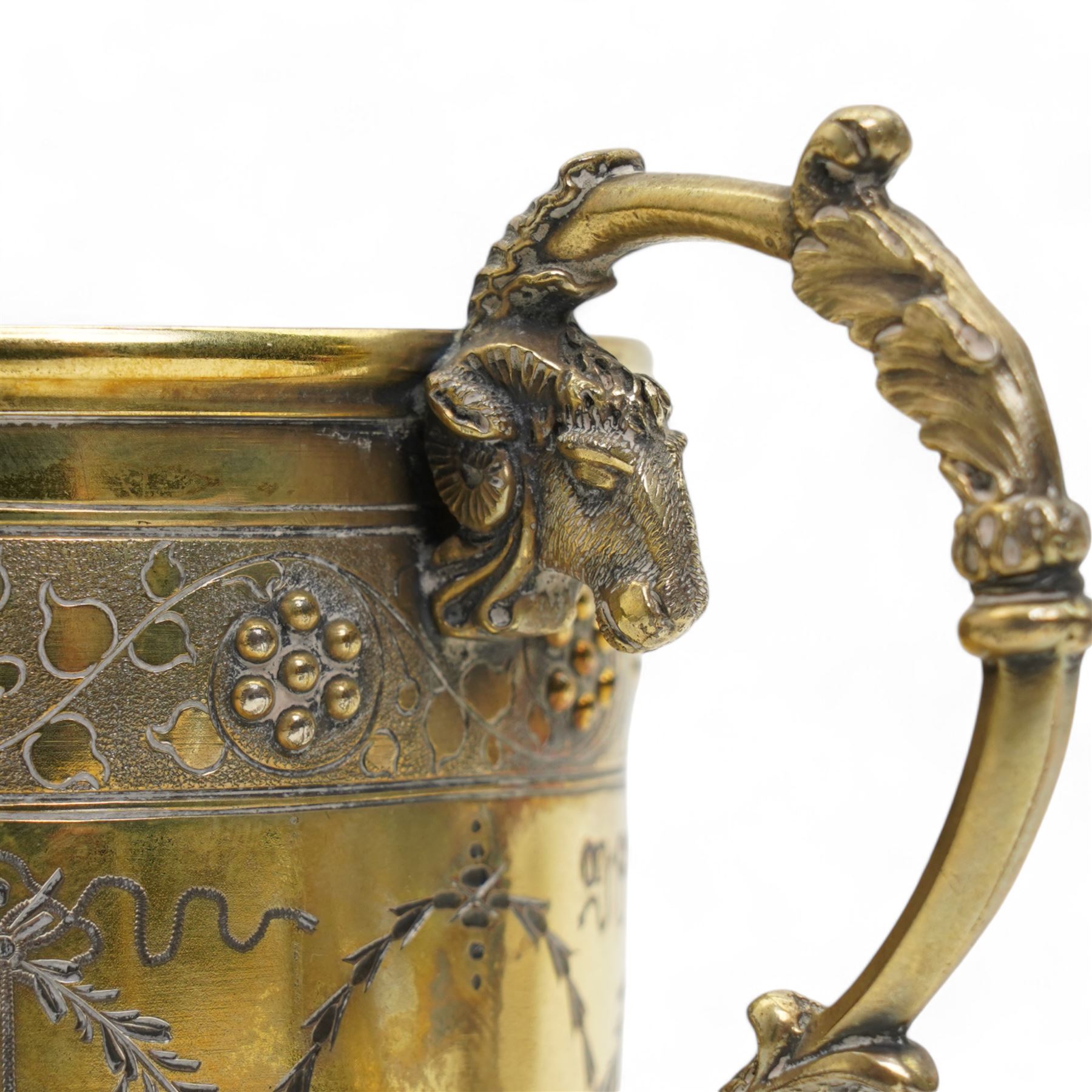 Victorian silver gilt christening mug of Gothic design engraved with trailing garlands with raised beaded flower heads and rams head handle H9cm London 1868 Maker Henry Holland in leather case