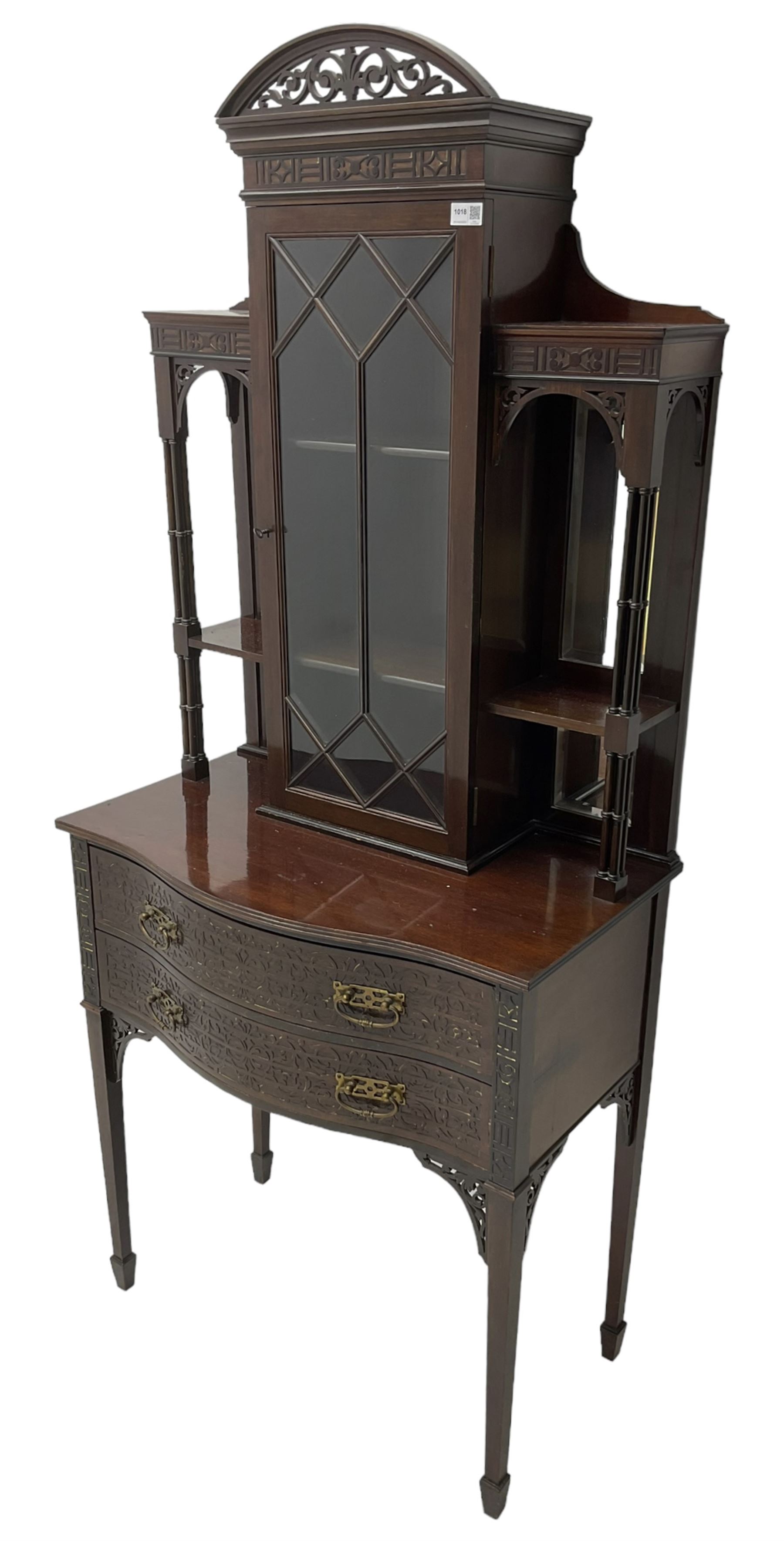 Early 20th century mahogany cabinet on stand, with pierced arched foliate pediment over blind-fretwork frieze, fitted with single astragal glazed door flanked by bevelled mirror back shelves with cluster column uprights, serpentine base fitted with two drawers with blind-fretwork facias 