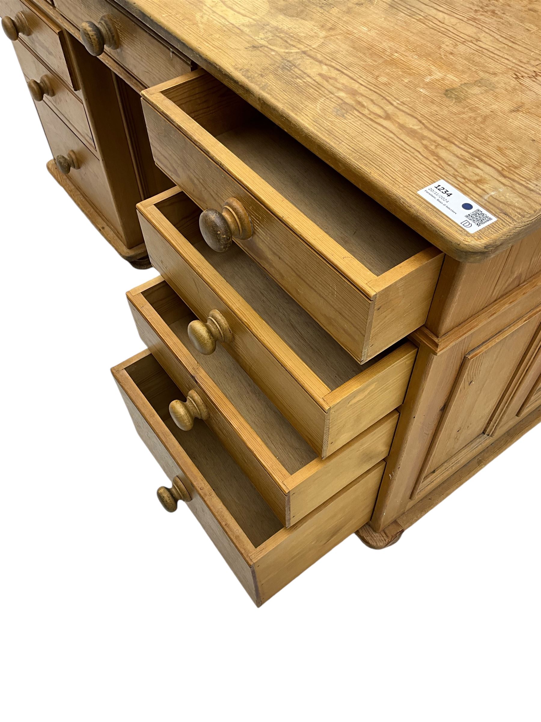 Waxed pine twin pedestal desk, rectangular top over nine drawers, on compressed bun feet 