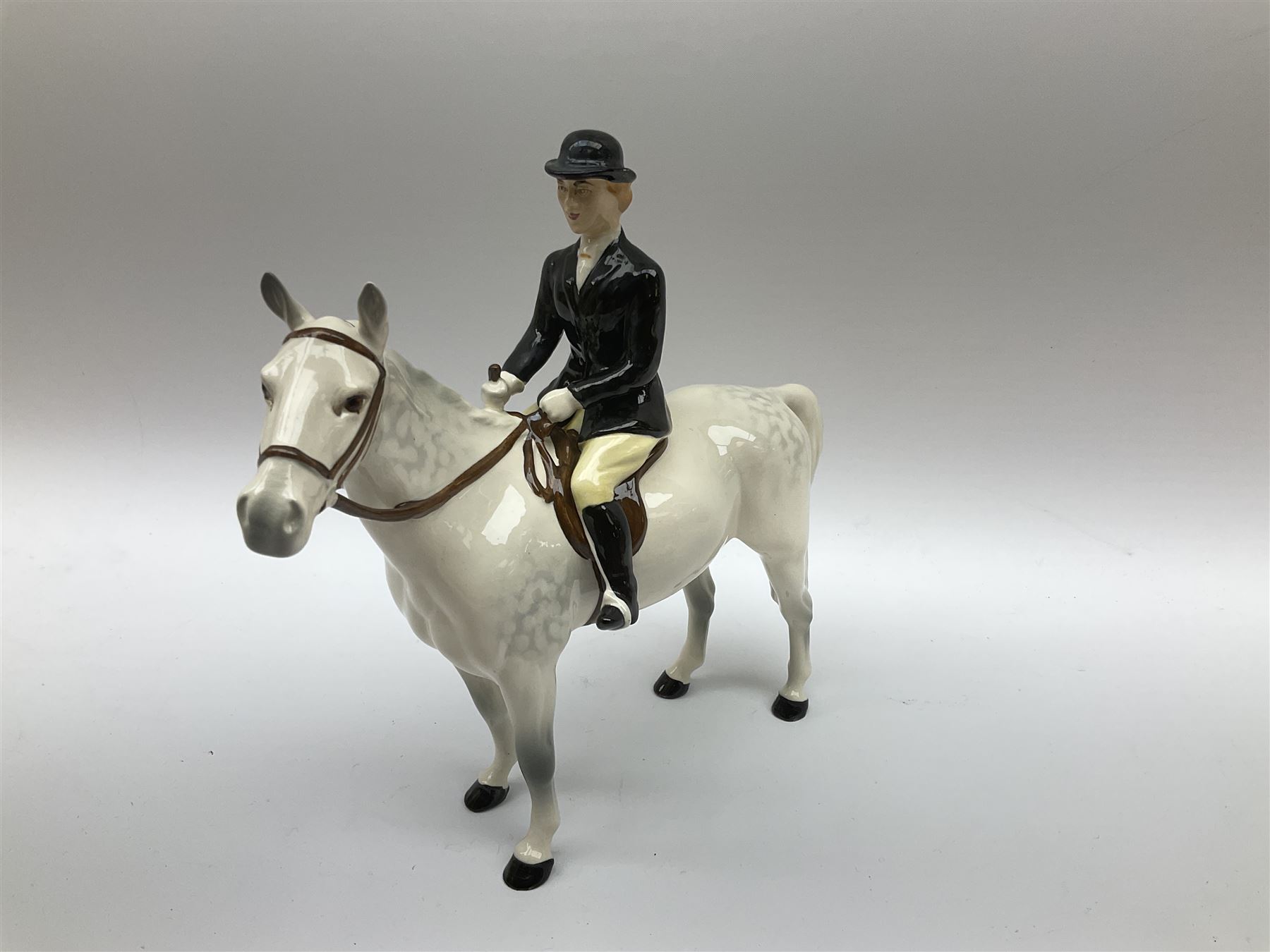 Beswick Hunting Group, comprising: two huntswoman on grey horses, model no 1730, huntsman on a bay horse, model no 1501, a seated fox, model no 1748, eighteen fox hounds and a spaniel, model no 967, all with printed marks beneath, together with three other ceramic huntsman on horseback and two hounds. 