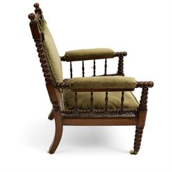 Late Victorian walnut bobbin turned armchair, curved cresting rail with bead moulding over turned spindle back, upholstered arms on turned balustrade supports, cane work seat over seat rail with matching bead moulding, loose seat cushion upholstered in olive green fabric, on tapering bobbin turned front supports with brass and ceramic castors, 