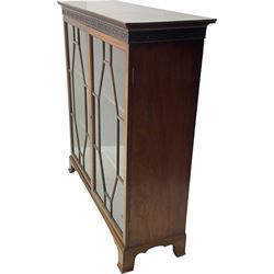 Early 20th century mahogany bookcase, projecting dentil cornice over blind fretwork frieze, enclosed by two astragal glazed doors, on shaped bracket feet 