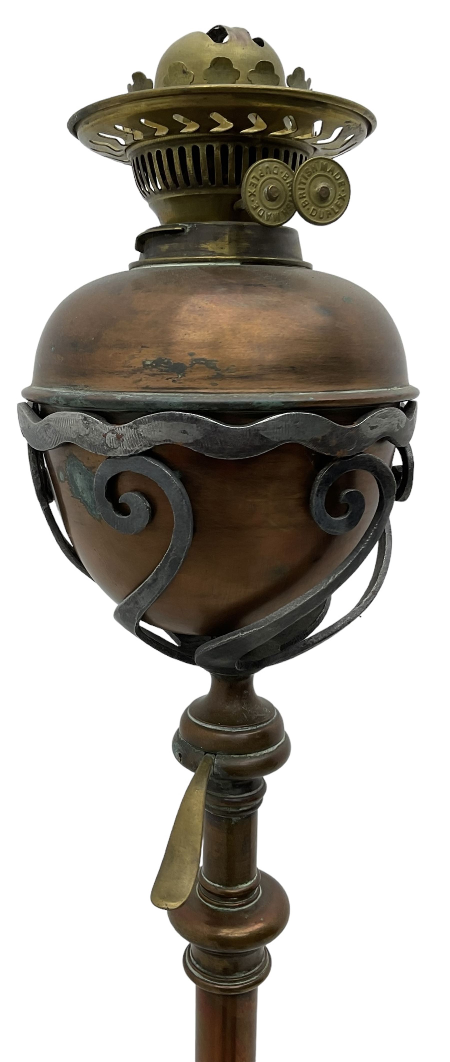 Late 19th to early 20th century wrought metal and copper telescopic oil standard lamp, the lamp and reservoir on scrolled supports with waved band, handle operating telescopic action, tripod base with scrolled terminals and twisted decoration, splayed pad feet 