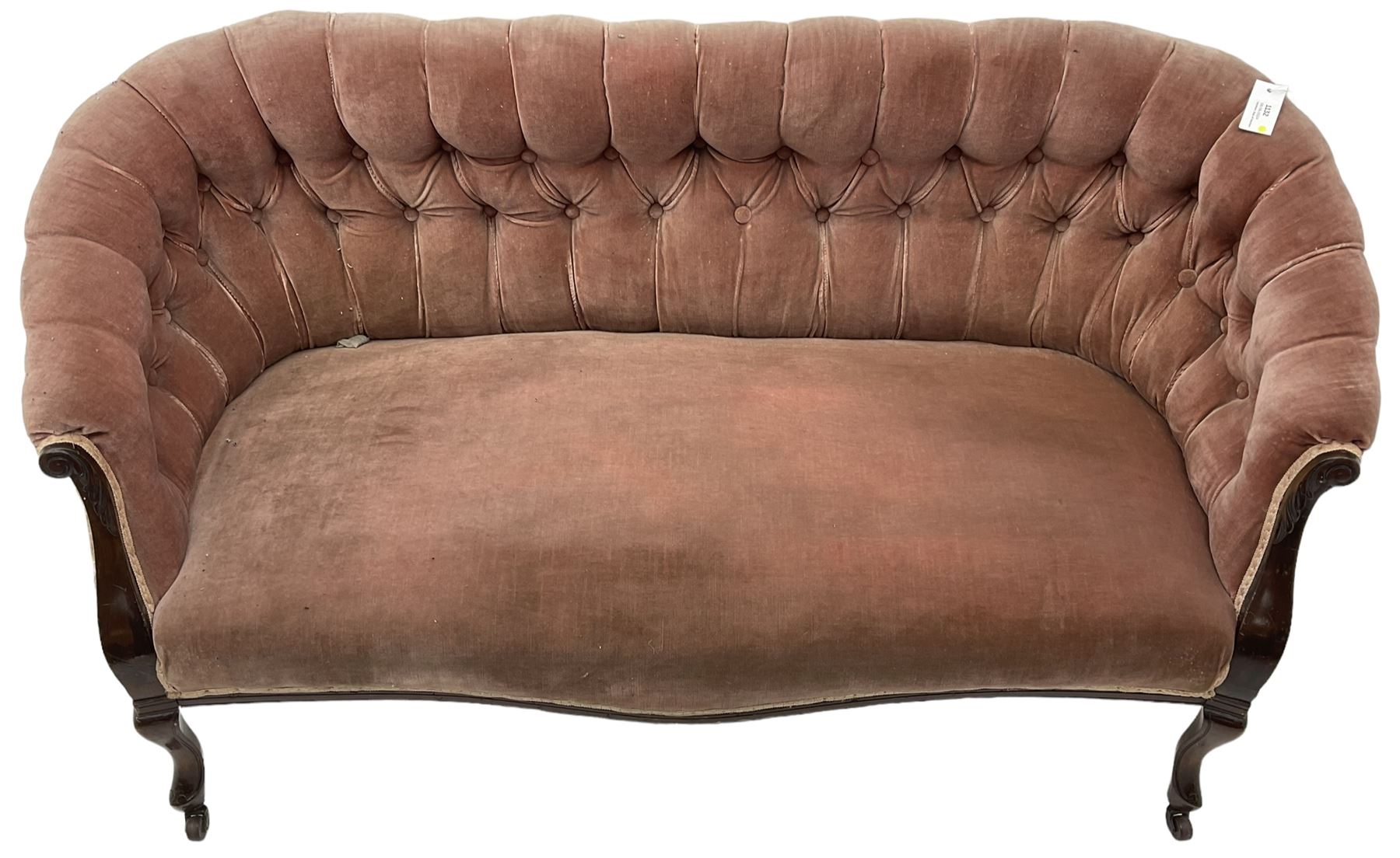 Late 19th century mahogany framed two-seat sofa, upholstered in buttoned pink fabric, on cabriole front supports, on castors 