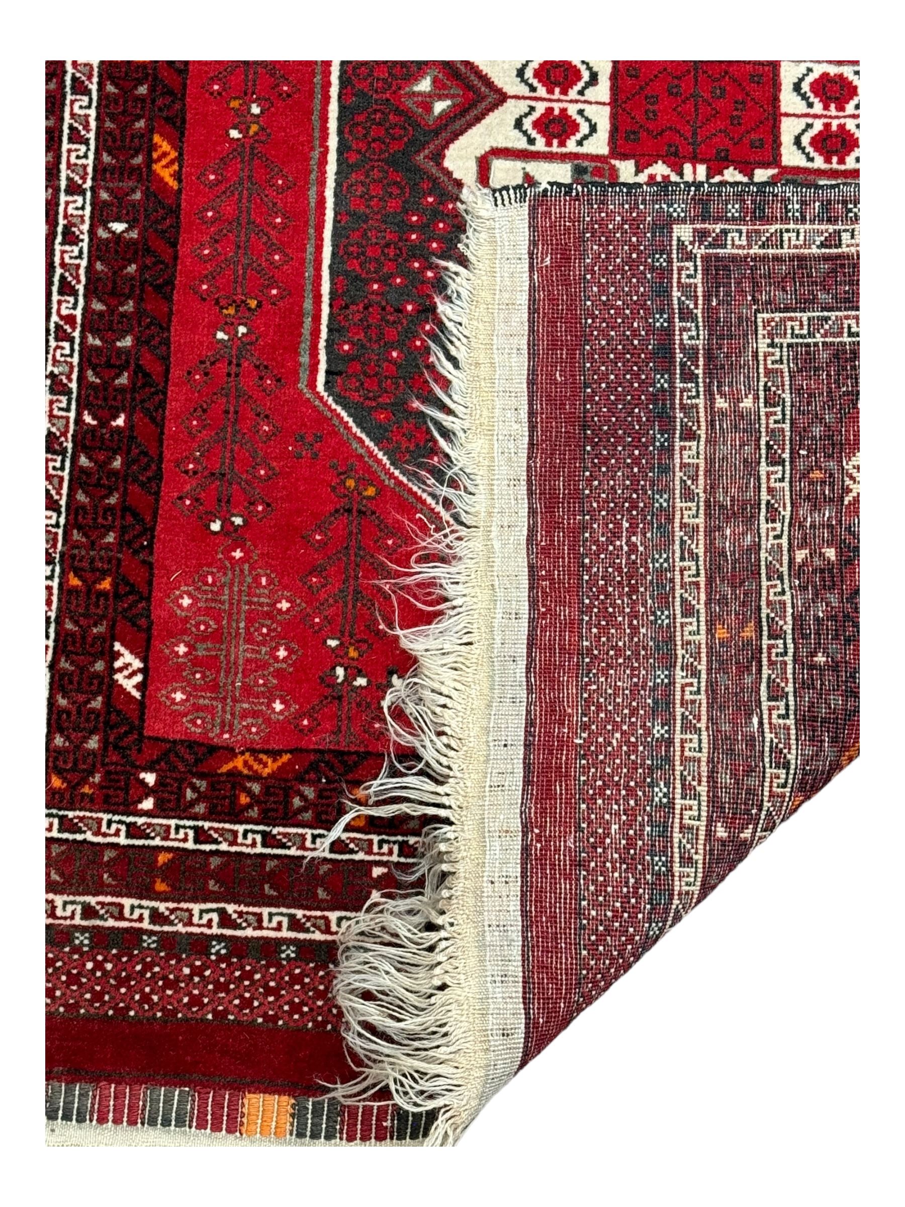 Persian Heriz red ground rug, the field with three large central medallions in indigo and ivory, border with geometric pattern within multiple guard stripes (119cm x 189cm); Persian Yomut crimson ground rug, central field with ivory medallion with geometric motifs, main border with geometric pattern within multiple guard stripes (88cm x 133cm)