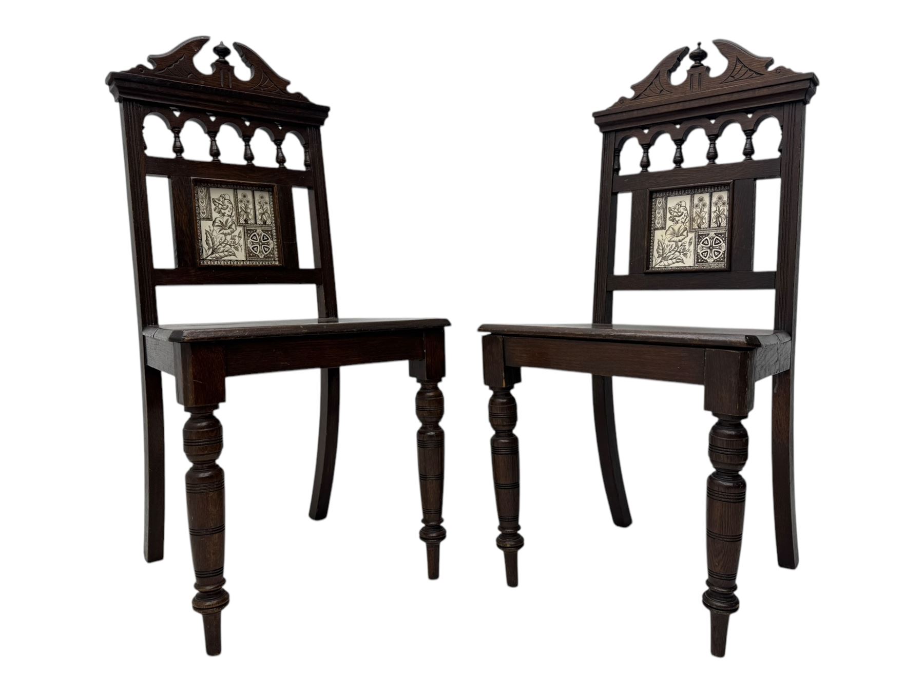 Pair of late Victorian oak hall chairs, shaped pediment over spindle turnings and tiled back, on ring turned supports 