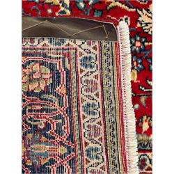 North west Persian Sarouk crimson ground rug, central floral medallion surrounded by scrolling branches decorated with foliage and stylised plant motifs, the main border decorated with repeating scrolling design with floral motifs, within guard stripes 