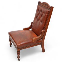 Late Victorian walnut matched two-piece salon suite upholstered in rust buttoned leather - open armchair, reed moulded frame and turned balustrade arm supports, on turned front feet with brass and ceramic castors (W60cm, H92cm, D70cm); nursing chair, fan carved cresting rail, moulded frame, on turned front feet (W58cm, H93cm, D73cm)