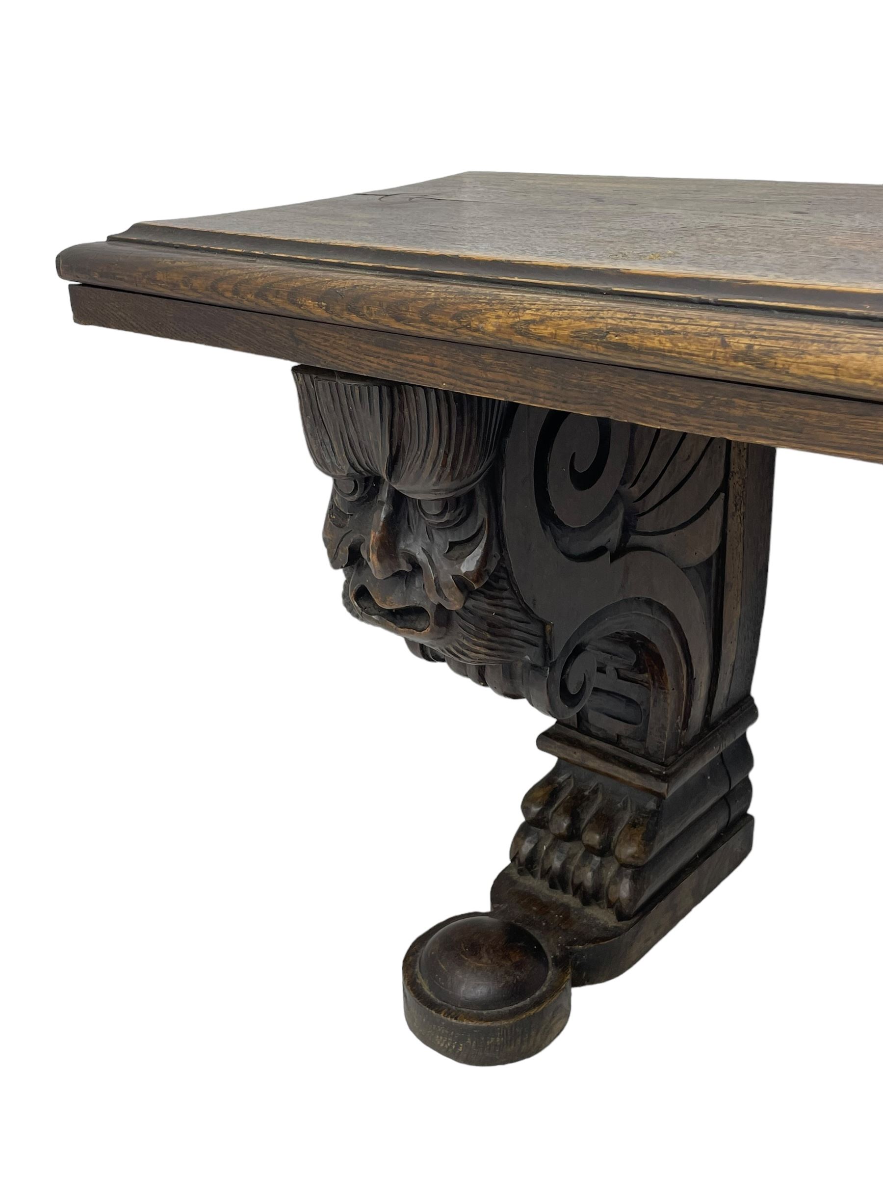 Victorian oak bench, moulded rectangular top, on mask and scroll carved corbel supports with paw feet, rectangular platforms with rounded terminals and applied roundel 