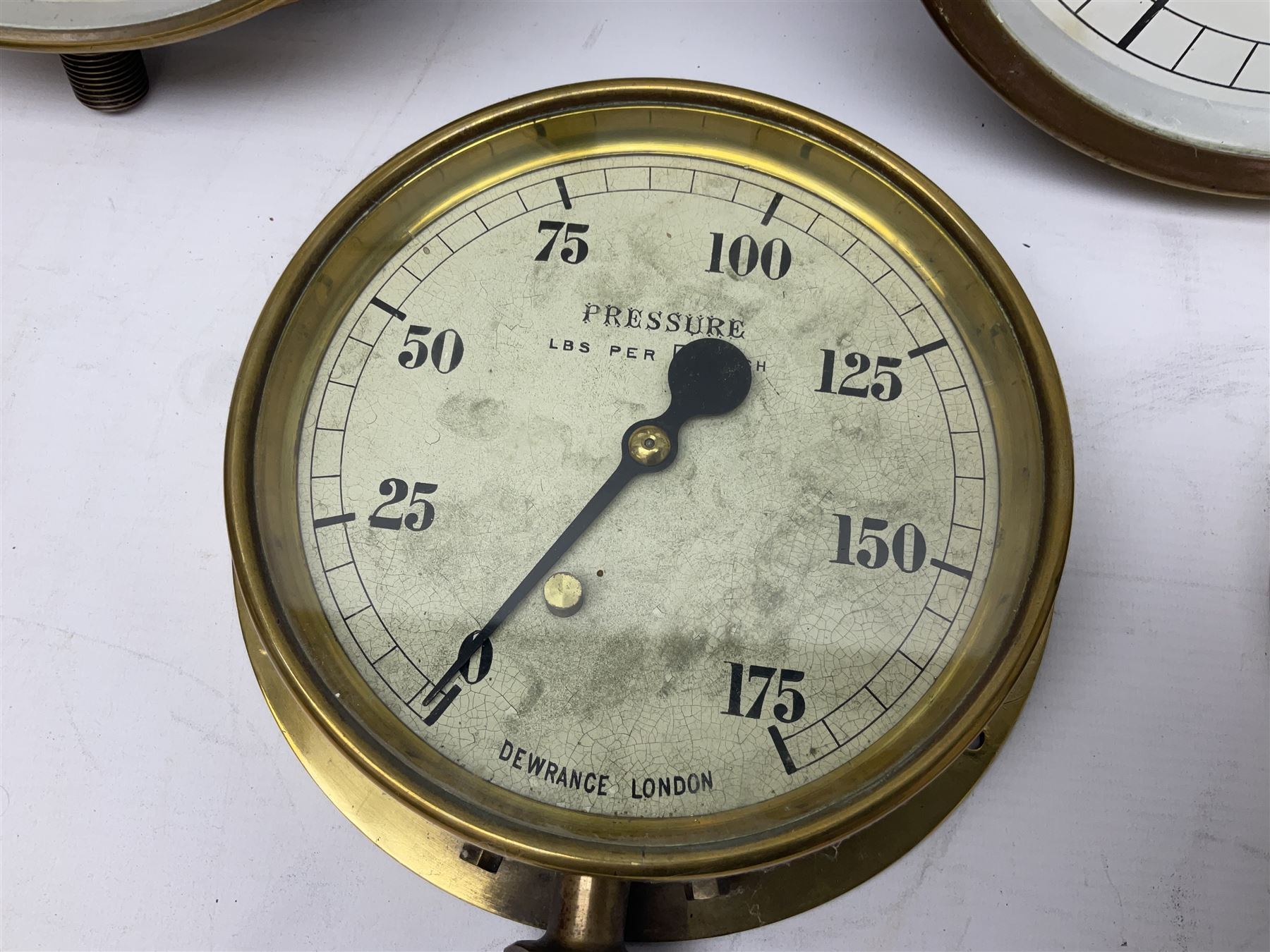 Four ship's brass cased pressure gauges by Dewrance London, Hopkinson Huddersfield, Bourdon and Bailey & Mackey Ltd; one with release valve; largest D29cm; and similar brass cased 'Water Level Below Surface' gauge by Thos. Matthews (Pumps) Ltd (5)