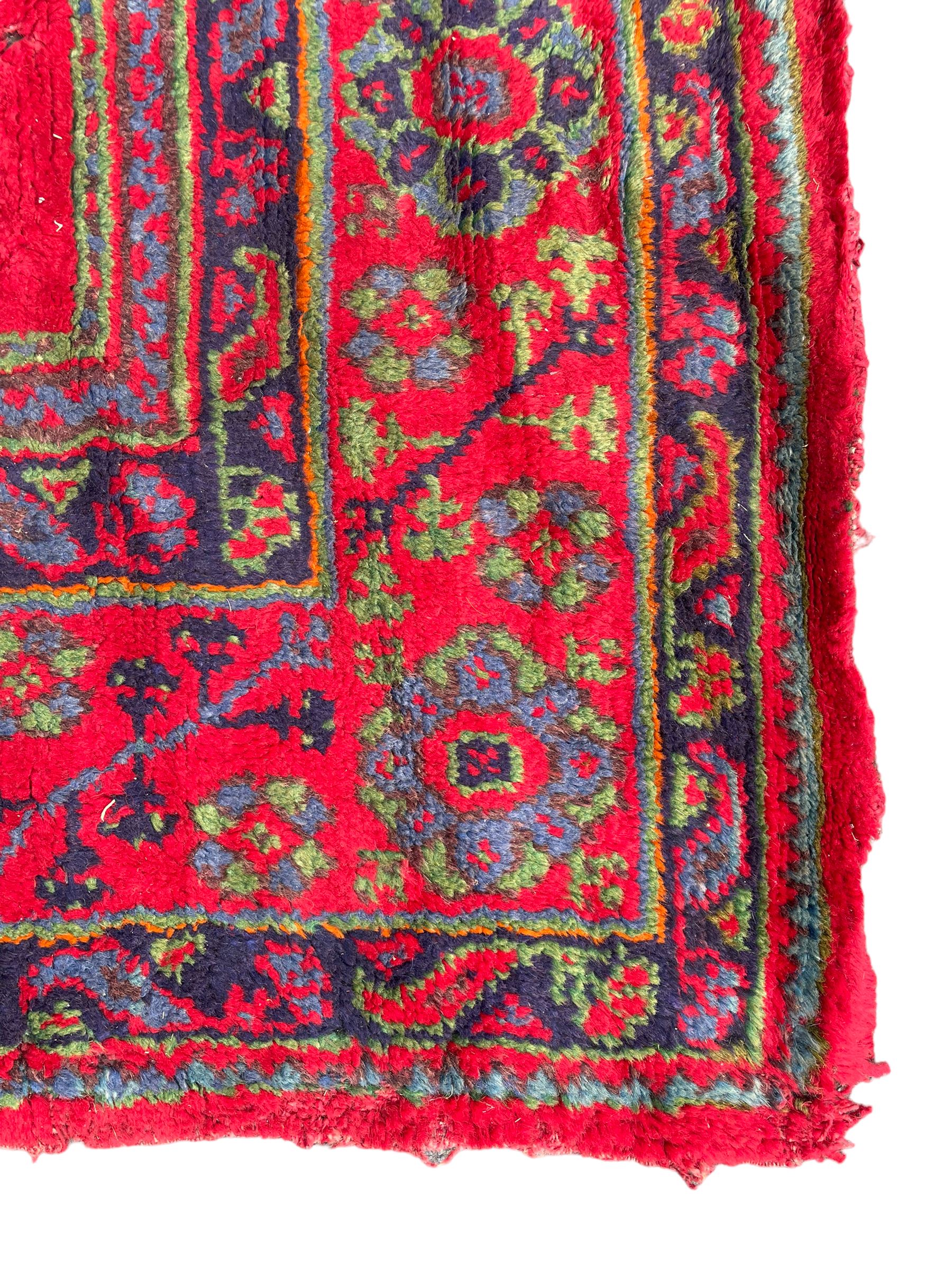 Early 20th century Western Anatolia Turkish Oushak crimson ground carpet, the field decorated with rows of Herati and Palmette medallions, the main border decorated with stylised flower head motifs within guard stripes