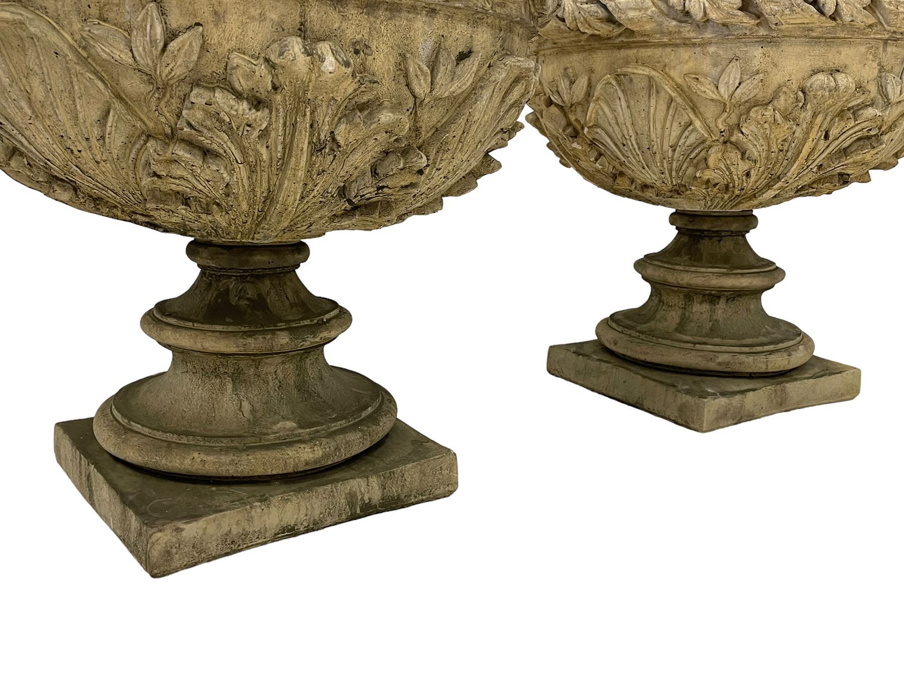 Pair of composite stone garden urn planters, acanthus leaf garland rim over foliate decorated body, stepped foot on square base