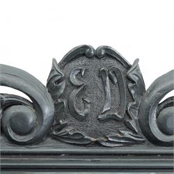 Late Victorian black painted mahogany wall mirror, scrolled pediment with central cartouche inscribed 'E.D', carved strapwork brackets and lower rail with turned supports, bevelled mirror plate 