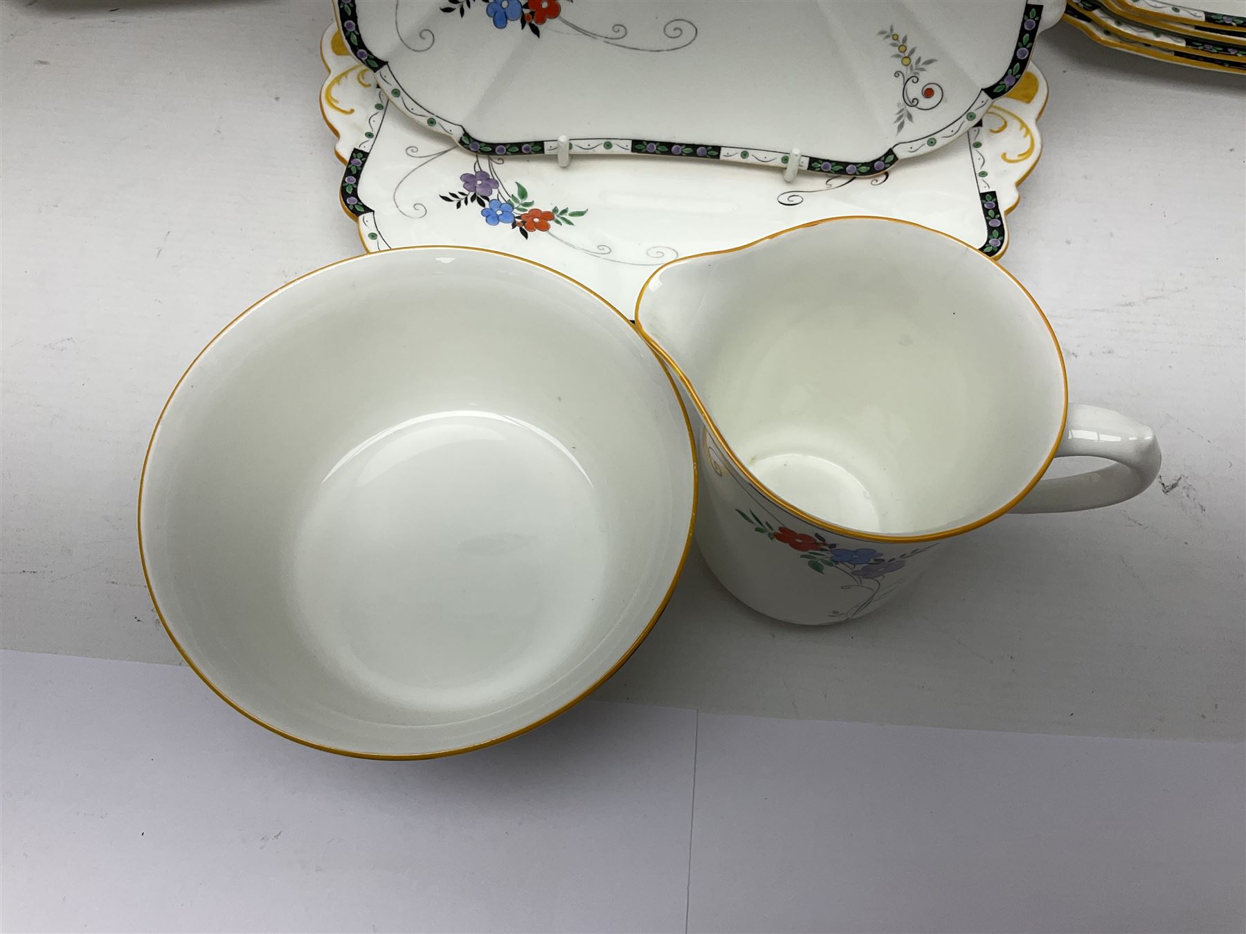 Art deco Shelley tea service for eight, decorated with floral sprigs, comprising teacup and saucers, dessert plates, two cake plates, milk jug and open sucrier, with to extra dessert plates