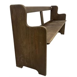 Early 20th century oak church pew or hall bench, open back over single plank seat, on shaped end supports