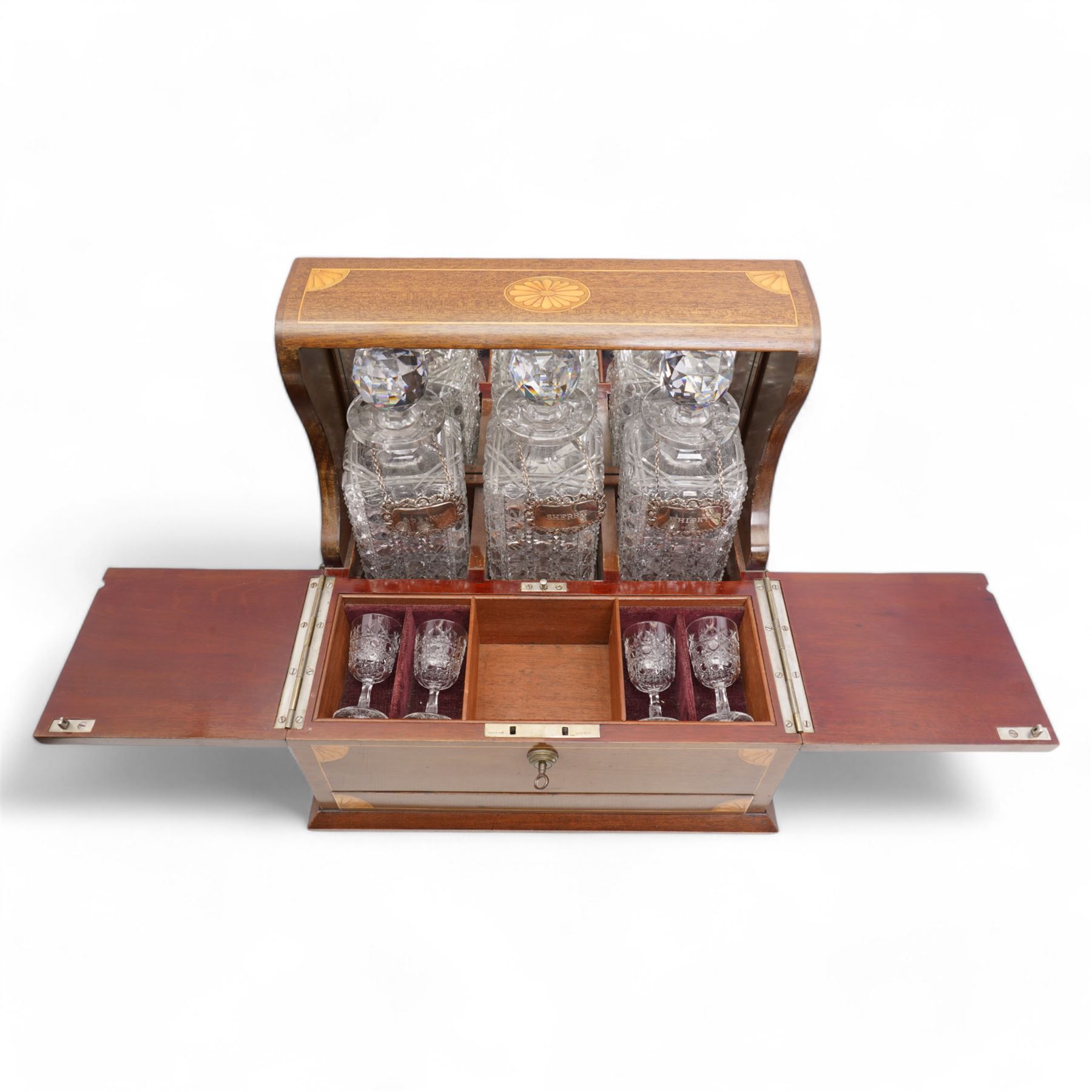 Edwardian walnut and boxwood inlaid tantalus games compendium, having three square section cut glass decanters, with associated silver Brandy, Sherry and Whisky labels, the two hinged doors with Bramah lock, open to reveal a fitted interior with four sherry glasses, over a secret sprung drawer to the base containing a selection of playing cards and cribbage board, L36cm x H32cm 