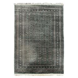 Pakistani Bokhara green ground rug, the field decorated with rows of repeating gul motifs, the main border featuring a series of smaller gul designs and geometric patterns, framed by multiple guard stripes