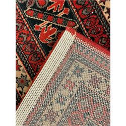 Persian design red ground rug, the field decorated with geometric motifs, repeating multiple band border 