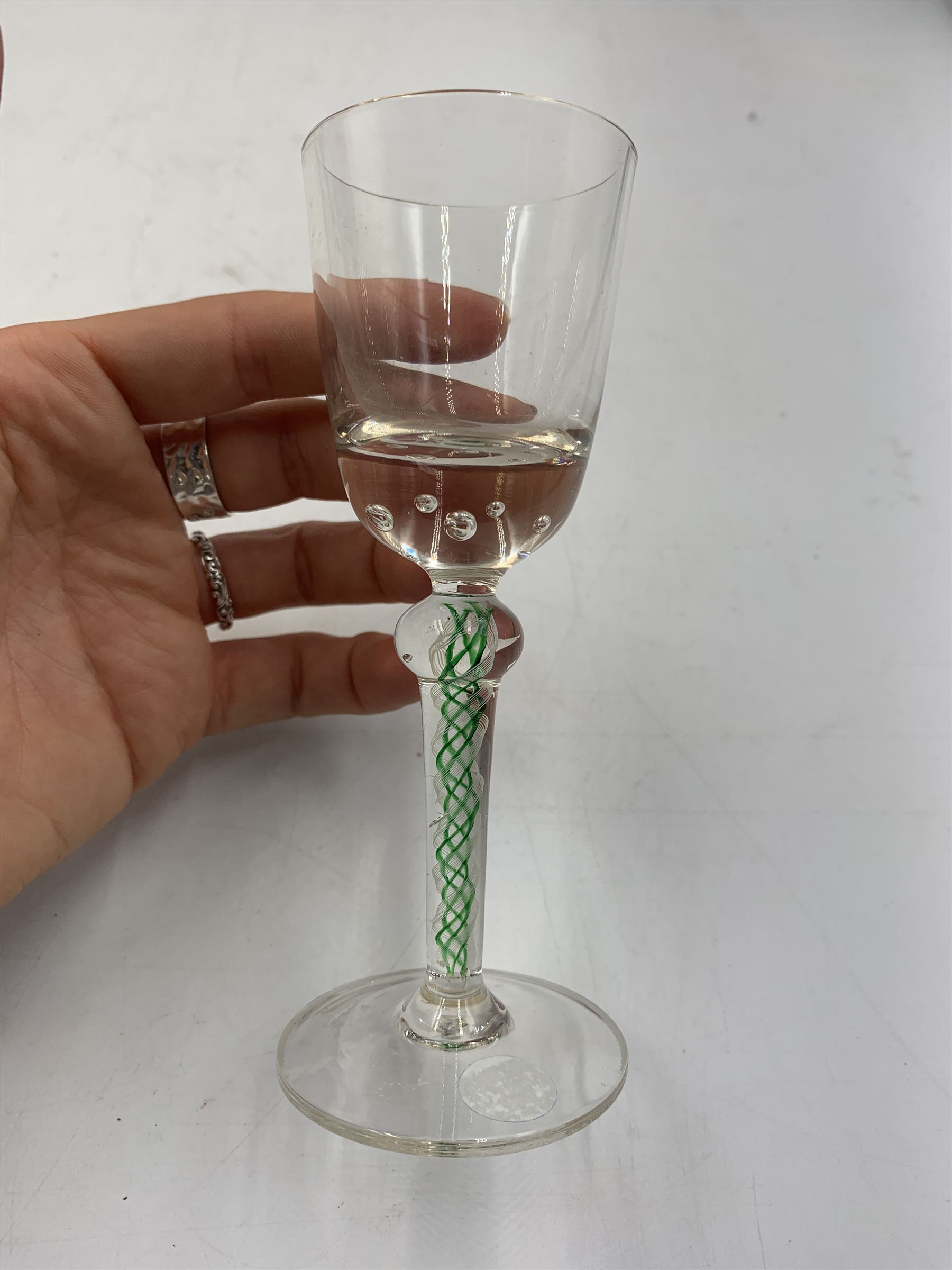 19th century continental liqueur glass, circa 1870, bucket bowl with bubble decoration, the tapered stem with green and white strands, H12.5cm; together with a Victorian aperitif glass, trumpet bowl decorated with foliate and fruiting vines, H10cm (2)