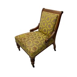 Late Victorian oak nursing chair, moulded frame with flower head carved roundels, upholstered in floral pattern fabric, on turned front feet with brass and ceramic castors 