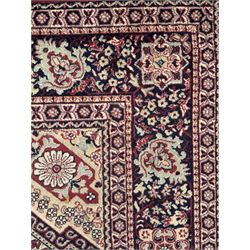 Persian Heriz design red ground carpet, the field decorated with a central star-shaped medallion surrounded by geometric floral motifs and angular vine patterns, the spandrels highlighted with palmette designs, the main border featuring a series of stylised rosettes and leaves against a dark blue ground, enclosed by multiple guard stripes with alternating floral and geometric motifs