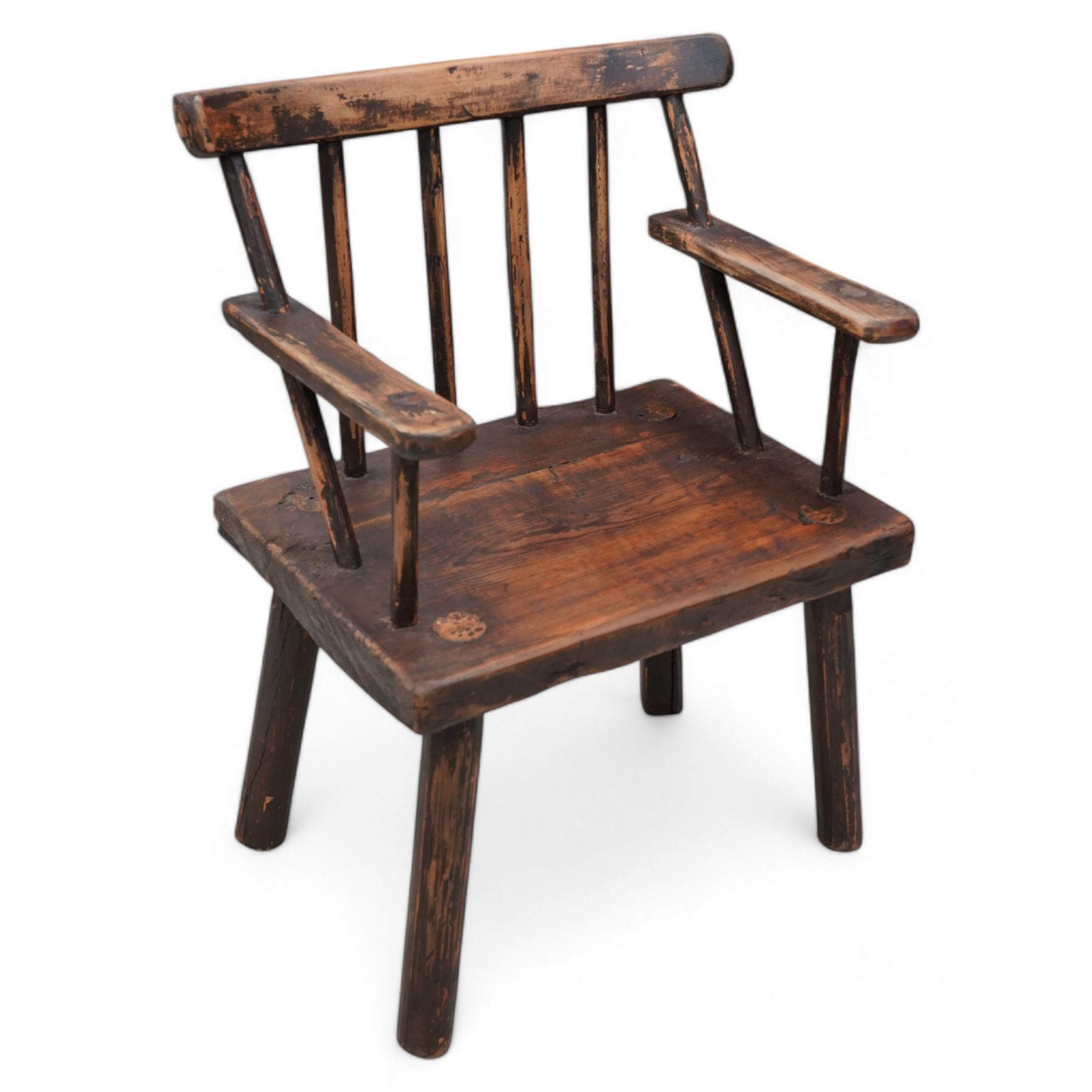 Vernacular 'Irish famine' or 'primitive' pine chair, bar cresting rail over spindle back, flat arms on thick plank seat, rounded supports 