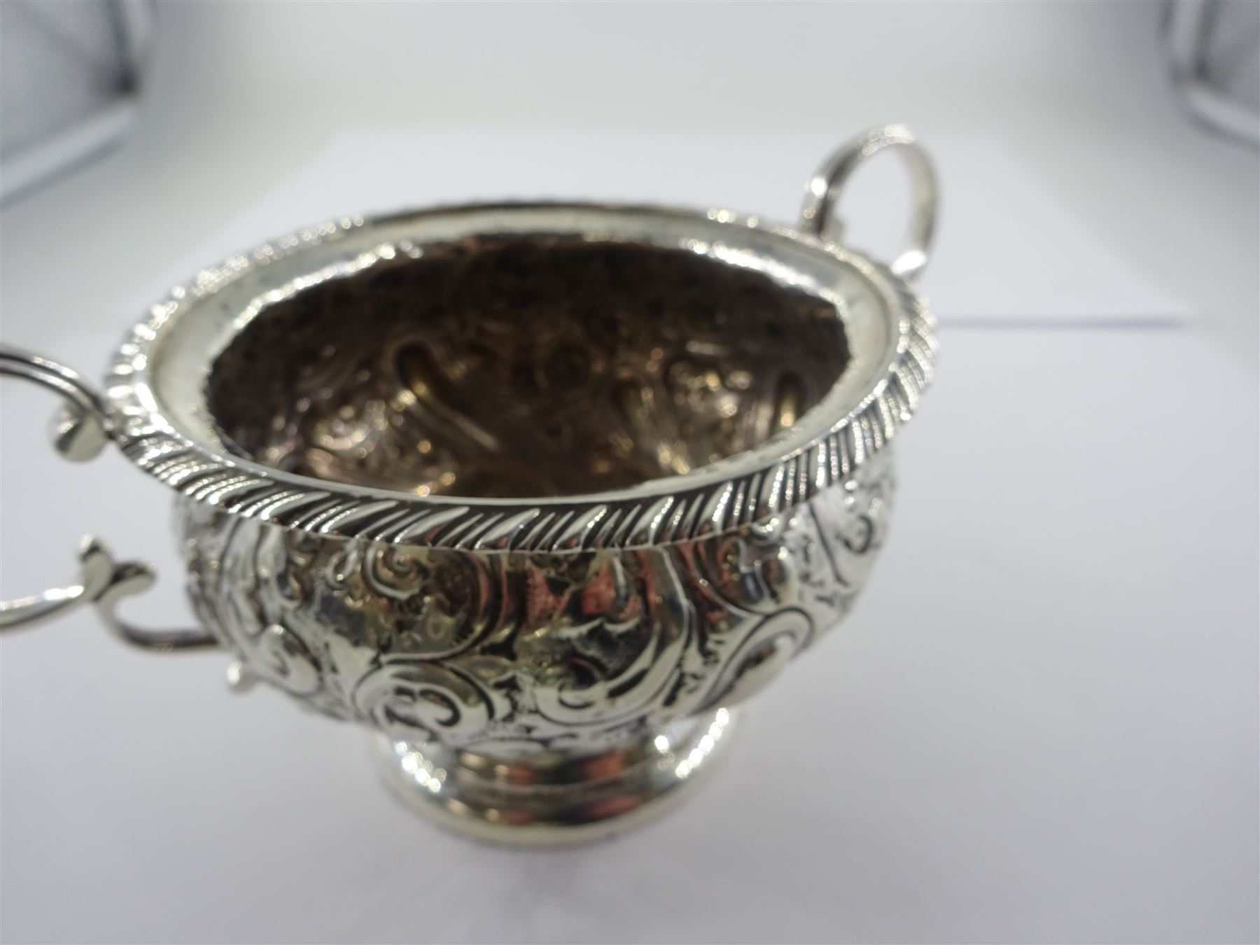 Late Victorian silver three piece bachelors tea service, comprising teapot, open sucrier and milk jug, each of bellied form, upon a circular stepped foot, and profusely embossed with foliate and scrolling decoration, the teapot with ebonised handle and finial, hallmarked George Nathan & Ridley Hayes, Birmingham 1894, teapot H14.5cm