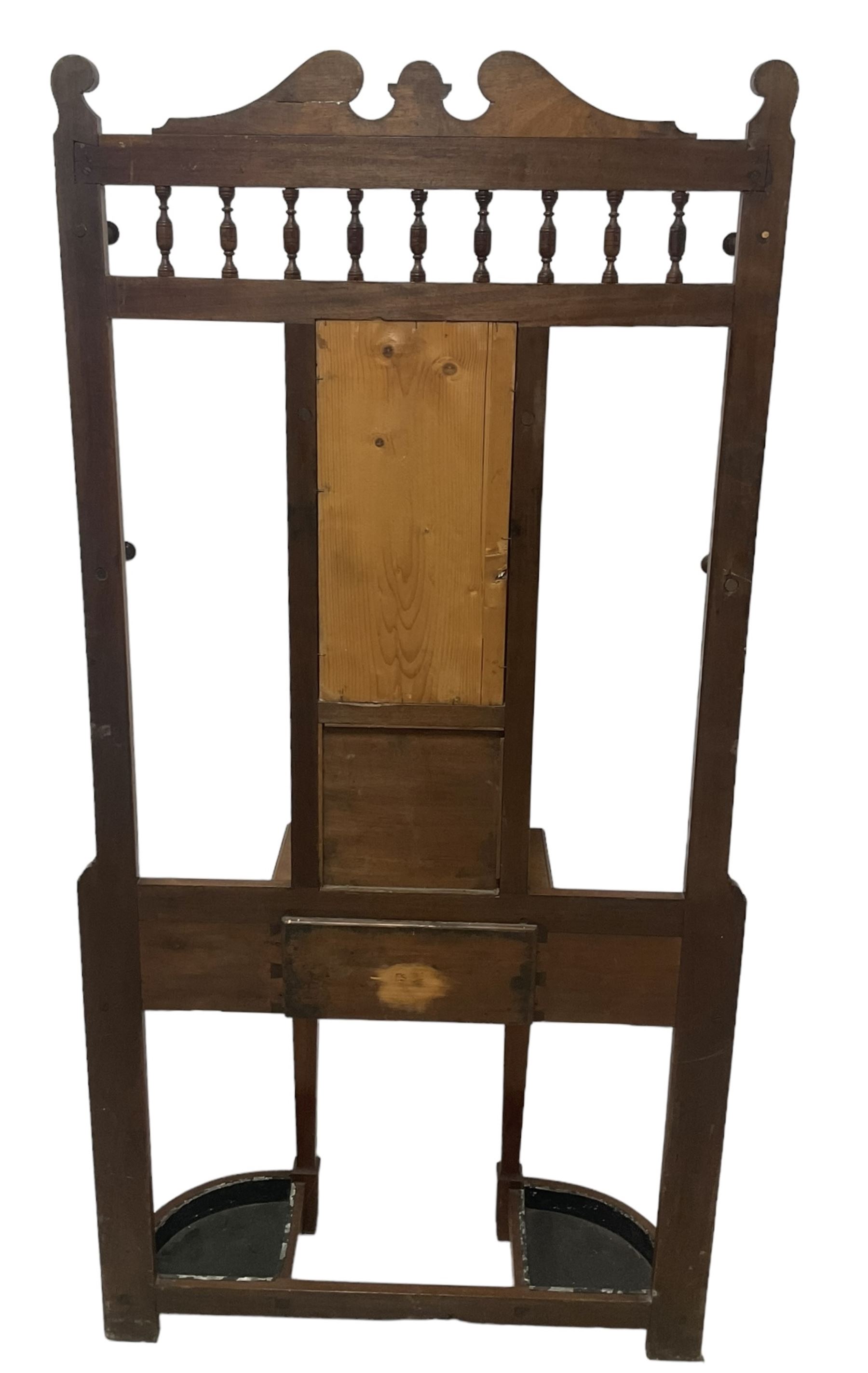 Late Victorian hallstand, raised pediment over balustrade frieze, bevelled mirror back with coat hooks over glove drawer, fitted with two drip-trays to base