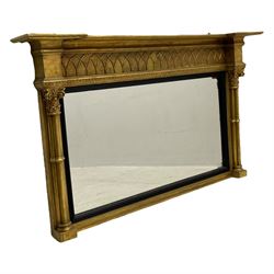 Regency design giltwood overmantel mirror, projecting cornice over pointed arcade frieze and foliate moulded upper edge, plain mirror plate within reed moulded ebonised slip, flanked by cluster columns with acanthus and scroll decorated Composite order capitals 