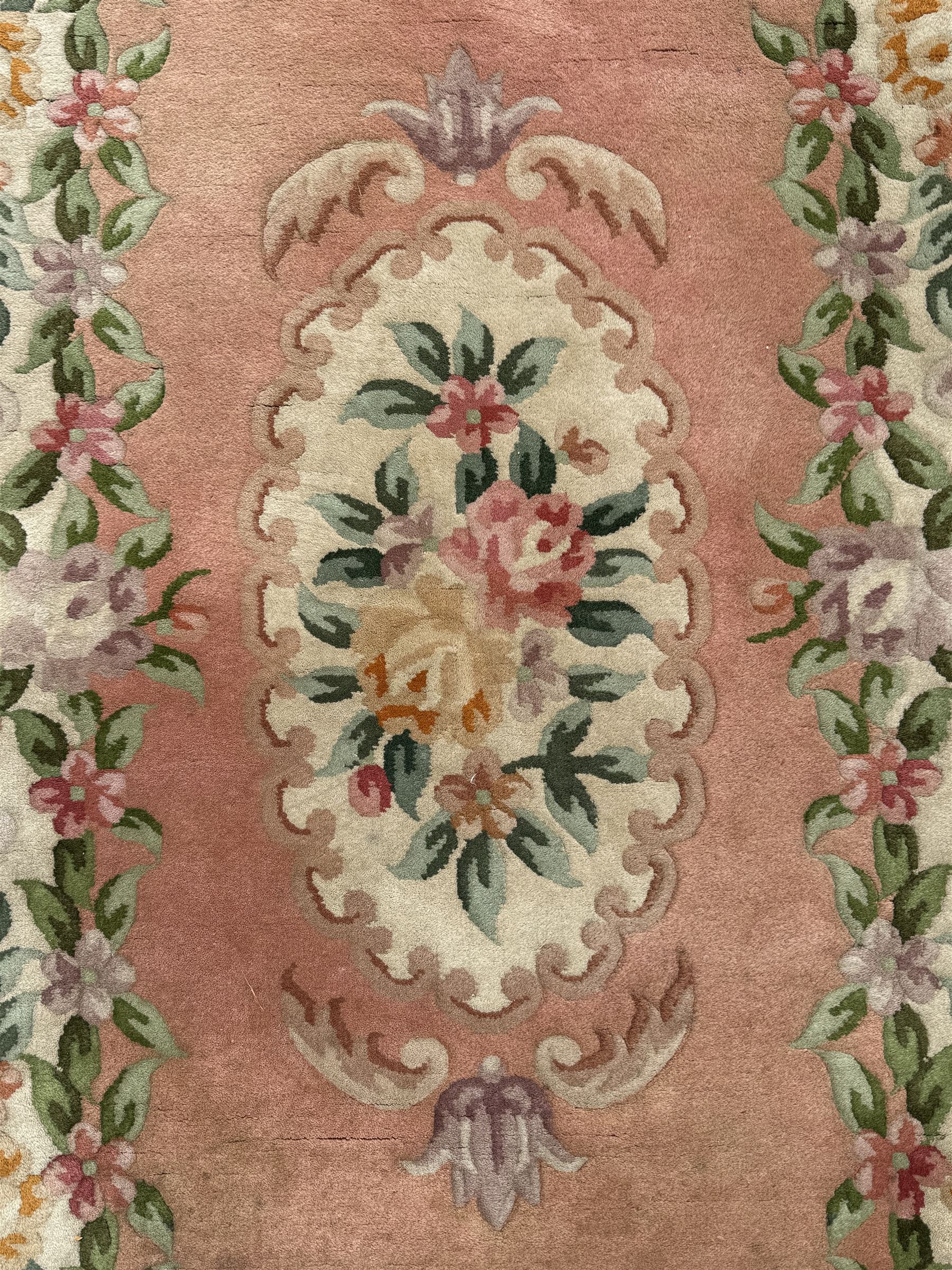 Chinese Aubusson design pink ground rug, the field decorated with an oval medallion filled with floral motifs in pastel shade, surrounded by floral garlands and foliate scrolls