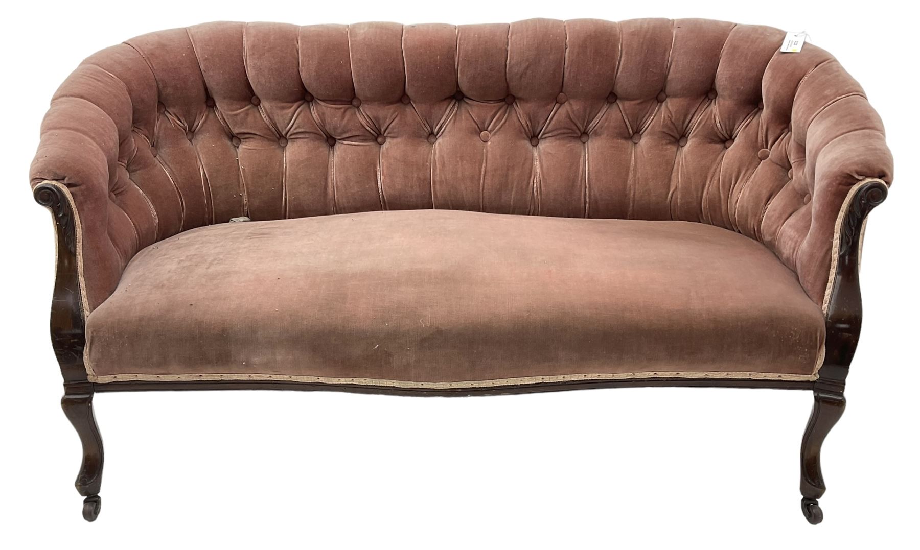 Late 19th century mahogany framed two-seat sofa, upholstered in buttoned pink fabric, on cabriole front supports, on castors 