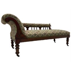 Late 19th century walnut framed chaise longue, upholstered in floral pattern fabric, rolled back rest and turned balustrade back, on turned feet with brass and ceramic castors 