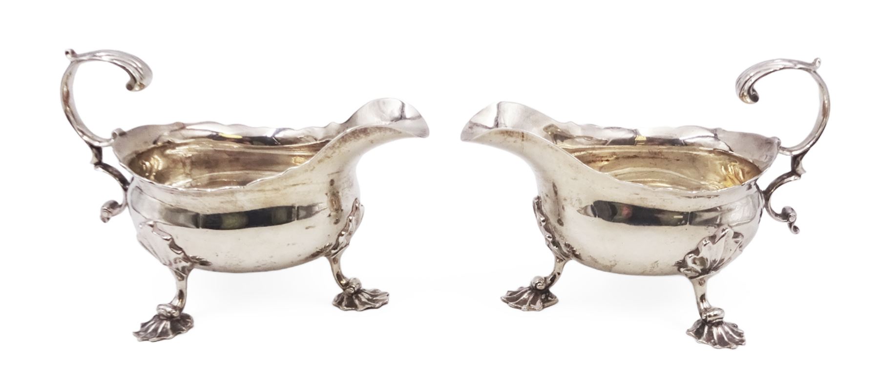 Near pair of George II silver sauce boats, each of oval form with shaped rim and capped flying scroll handle, upon three scroll mounted feet, hallmarked David Hennell, London 1758, H12cm