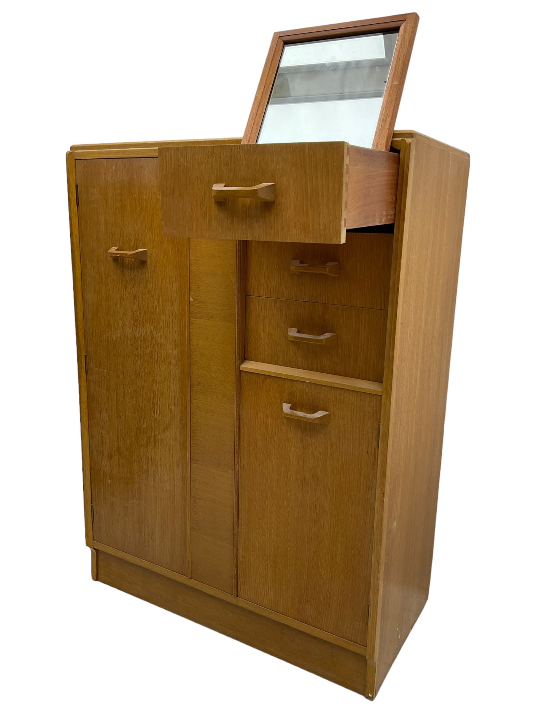 G-Plan - mid 20th century teak tallboy or combination wardrobe, left side with full-height hanging cupboard, right side with three drawers, the top fitted with vanity mirror, above cupboard with shelves, raised on a plinth base