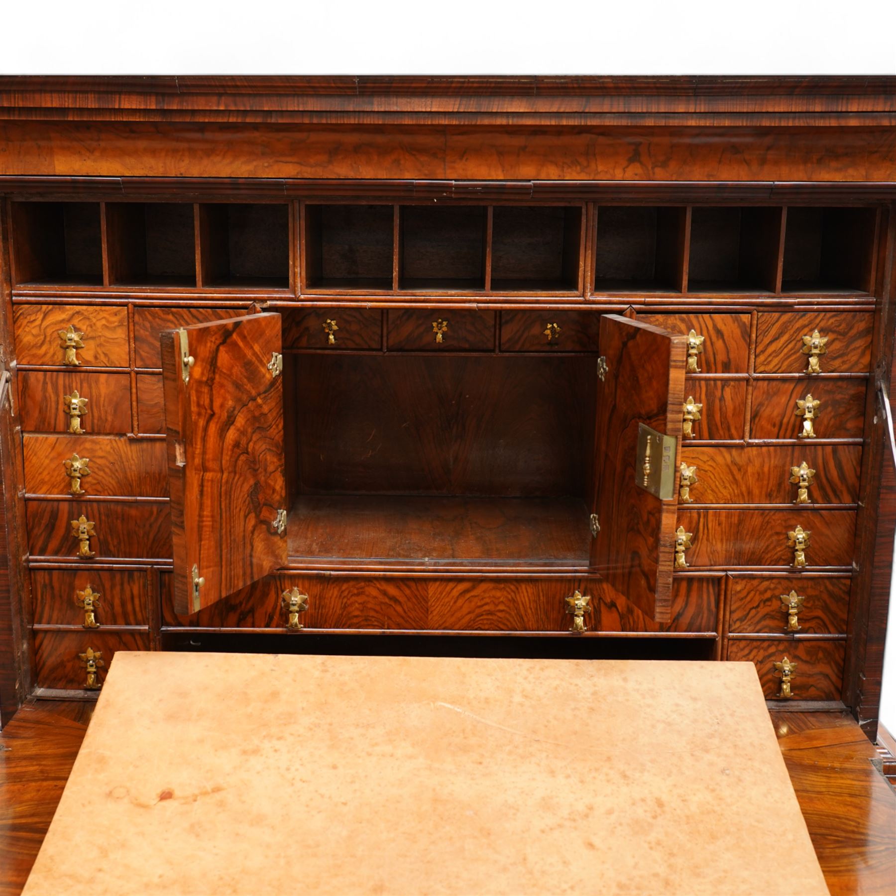 George II figured walnut escritoire, projecting moulded cornice over cavetto frieze with drawer, figured fall front revealing pigeonholes, a combination of drawers, central double cupboard and hidden drawers, fitted with two short and two long drawers, cast gilt metal escutcheons and drop handles, on turned feet 