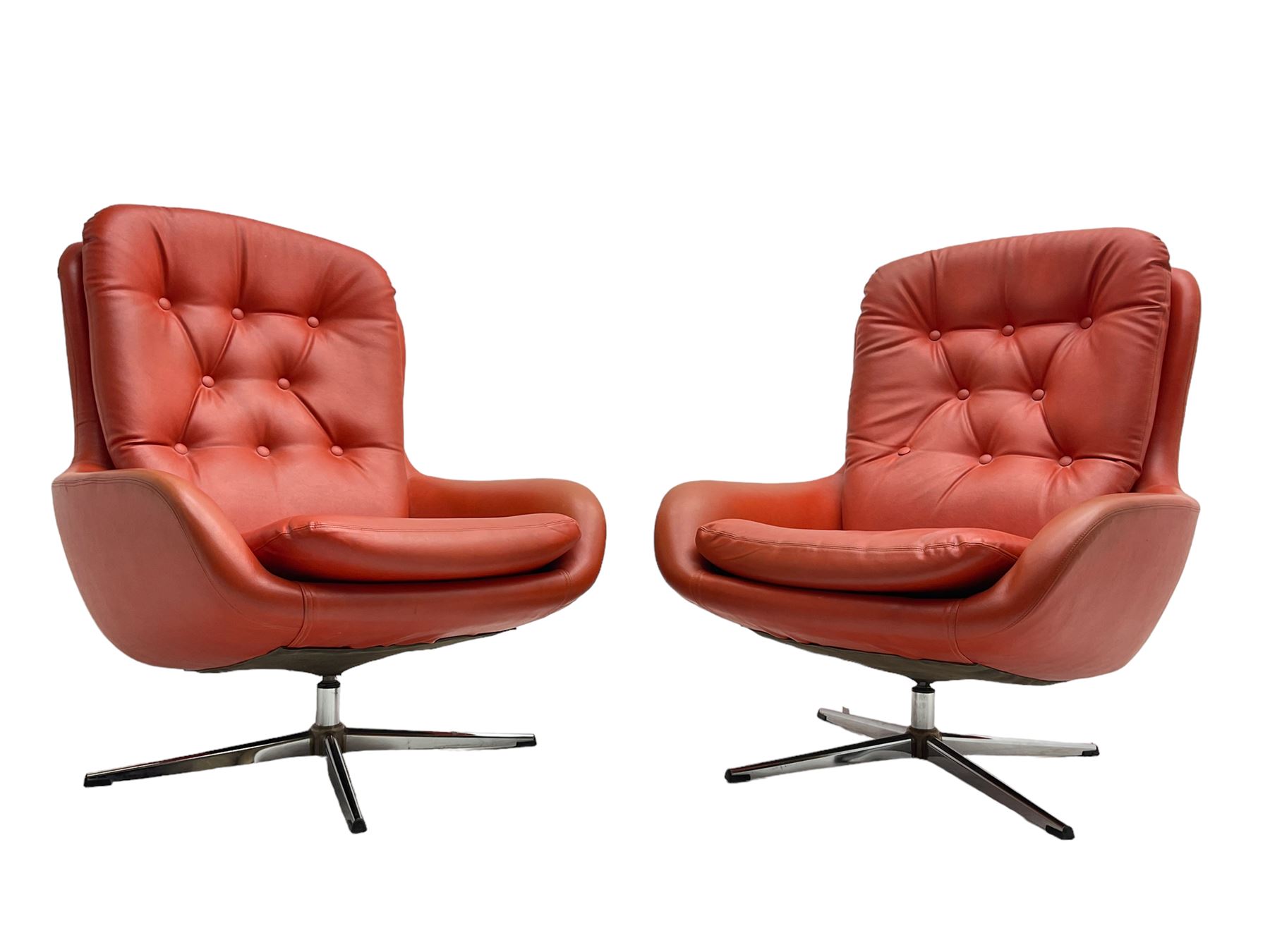 Pair mid-20th century circa.1974 swivel lounge chairs upholstered in buttoned red faux leather, on polished metal base