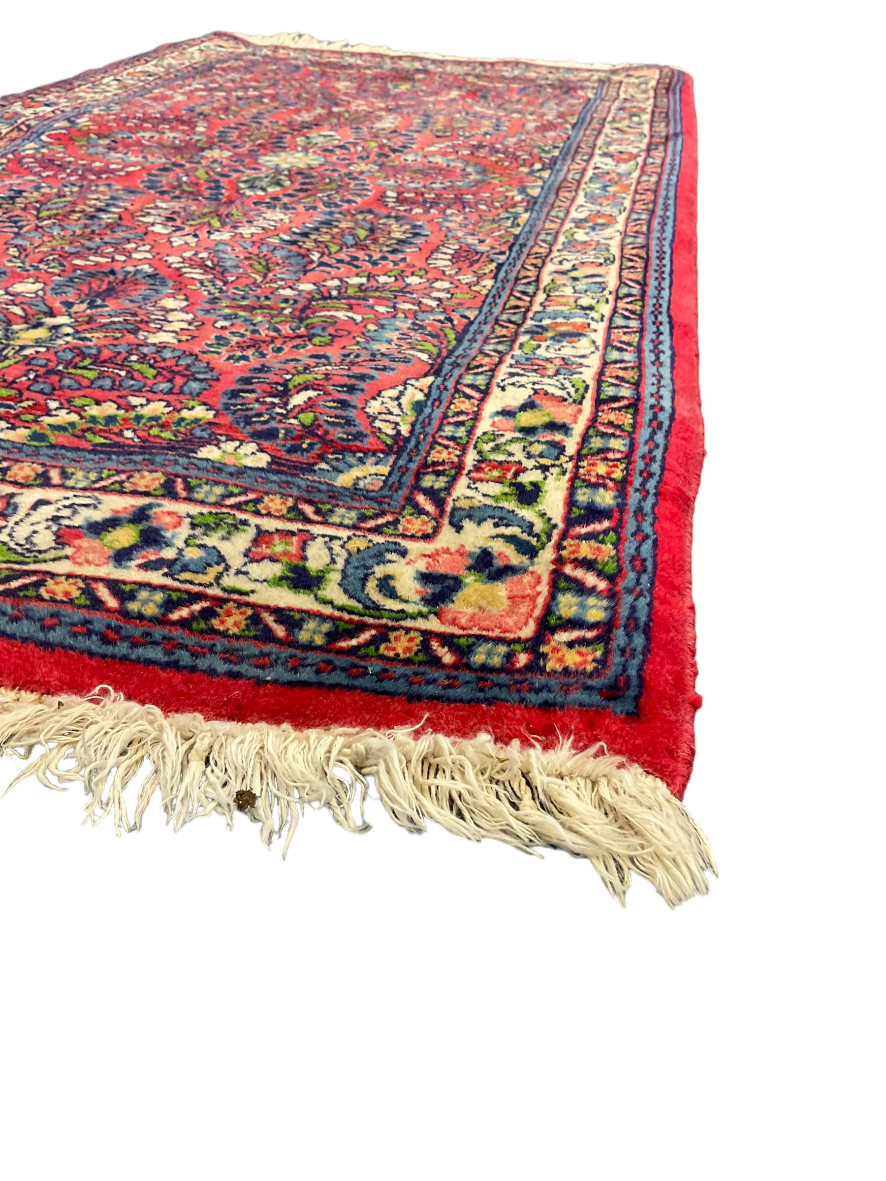 Small Persian red ground rug, the field decorated with an overall floral design, guarded ivory ground border decorated with trailing flower heads and foliage